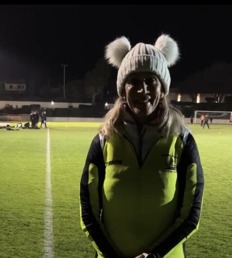 Coach de course à pied donnant des consignes à un groupe de coureurs sur une piste.